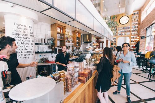 employees serve customers at a crowded coffee shop