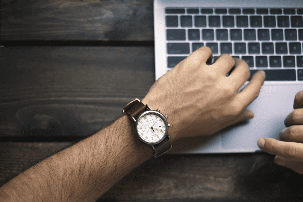 employee working at a laptop checking their watch