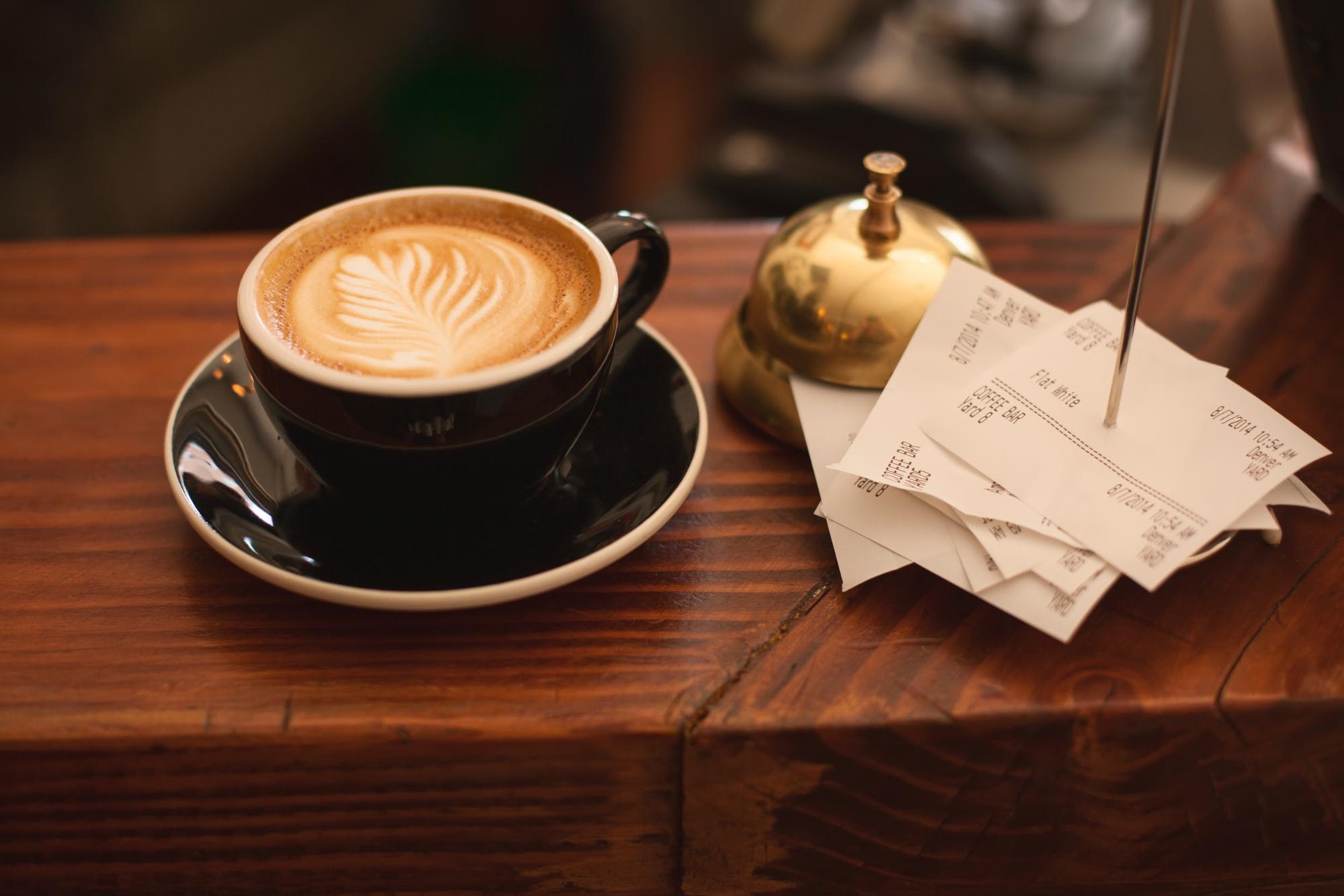 latte sitting next to a stack of receipts at a coffee shop