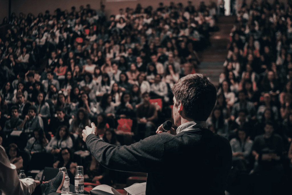 man describing qualities of a manager to a crowd