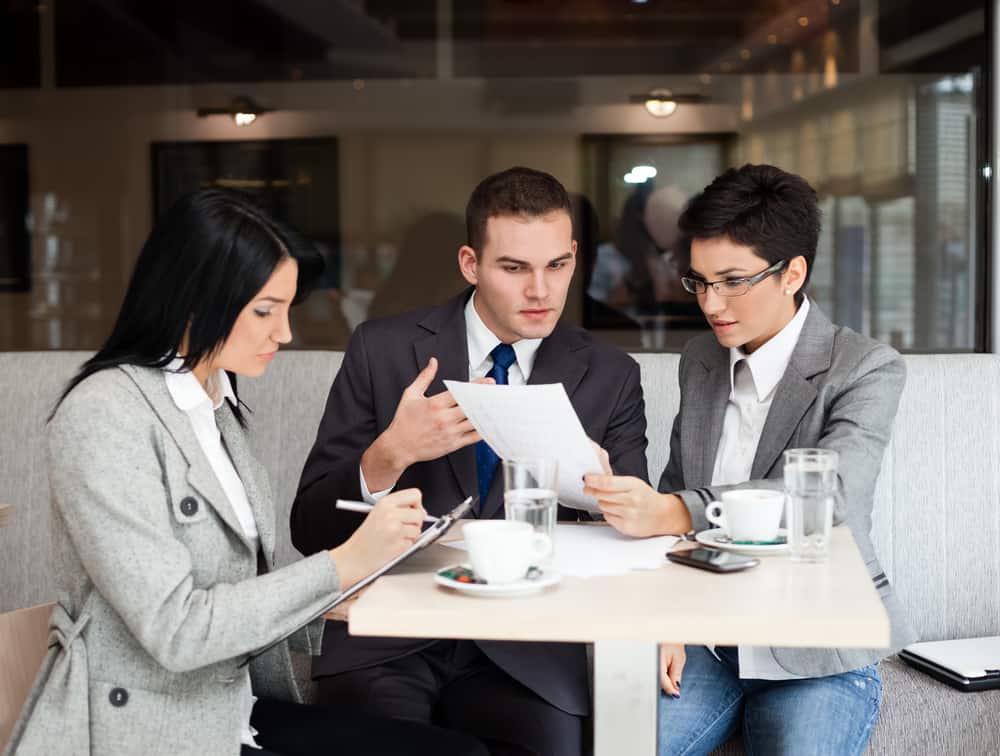 Young business people working over a paperwork and drinking coffee