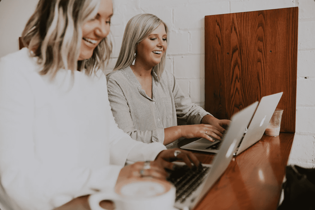 Two professional women sitting next to each other working on their laptops