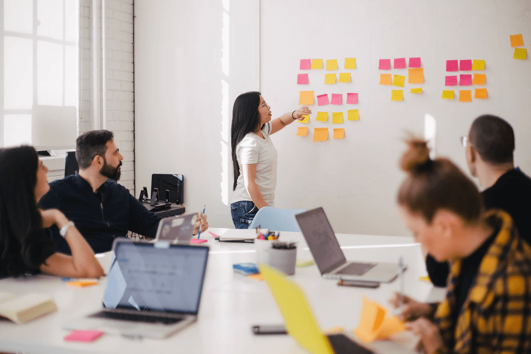 Woman using sticky notes on a whiteboard training her employees 