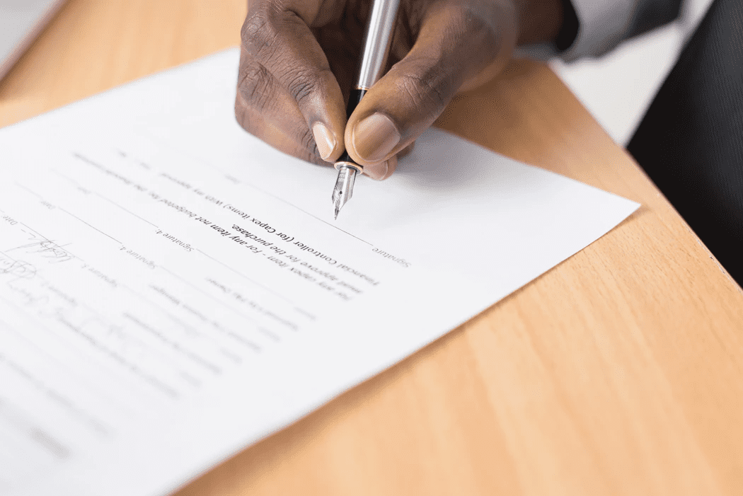 Hand of a manager holding a pen to sign employee discipline form