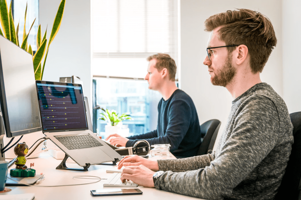 Two men on computers working at the same table