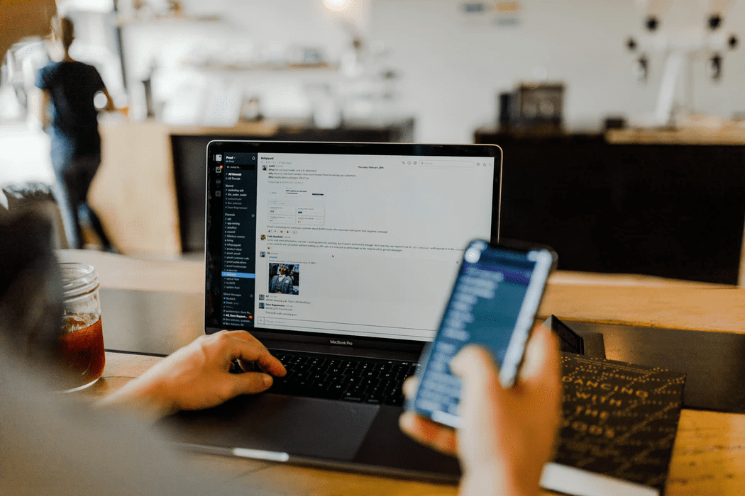 manager creating an employee schedule with his phone and laptop