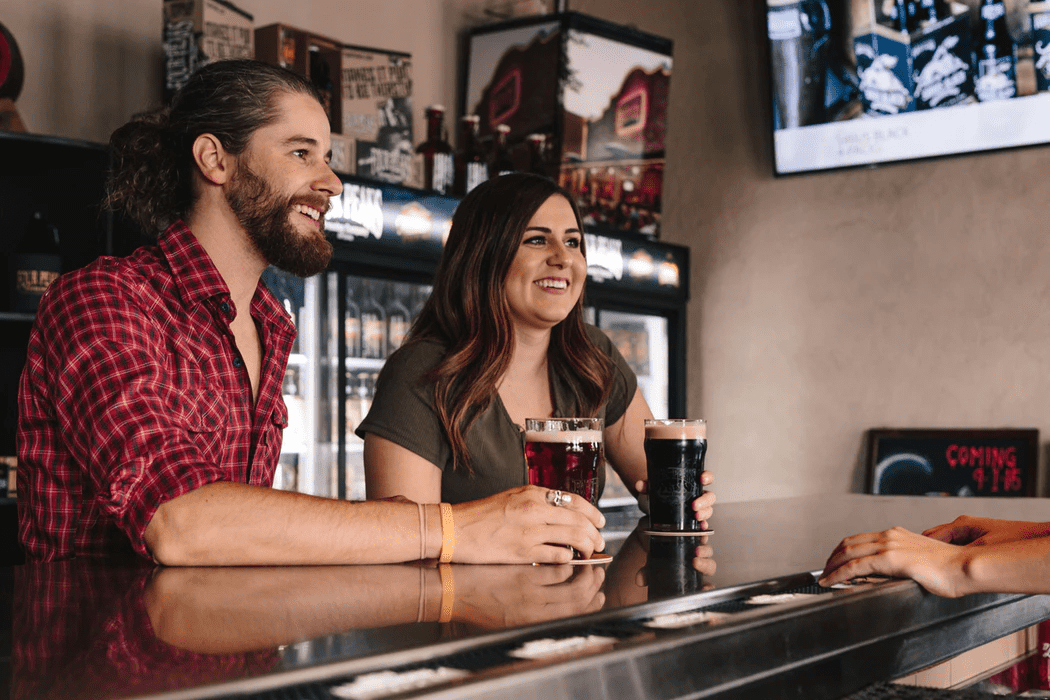 Man and woman drinking beer and discussing owning a bar