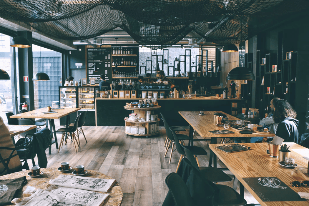 Coffee shop with wooden floors and tables, netting hanging from ceiling