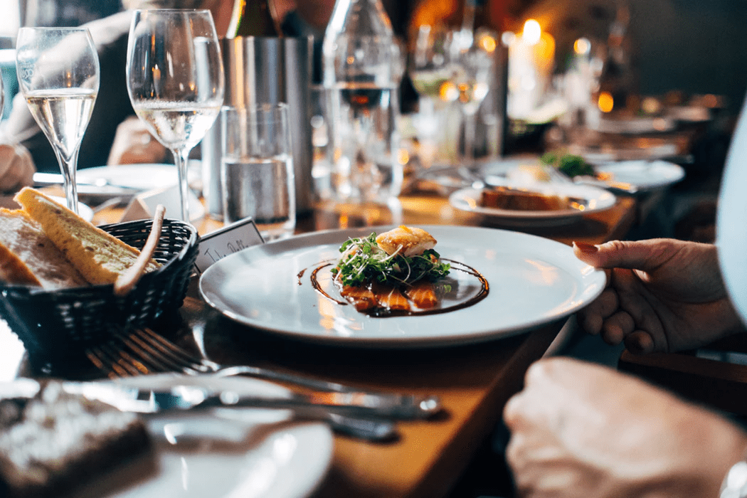 viinilasit ja illallislautaset pöydällä kuvaamassa ravintolan missiota's mission statement