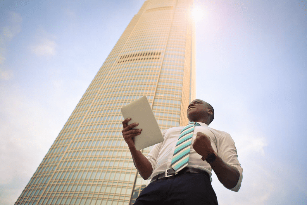 Business owner standing outside a tall building, celebrating success with workforce optimization