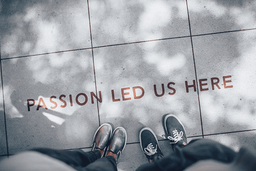 Two People]s feet standing on concrete that says Passion Led Us Here