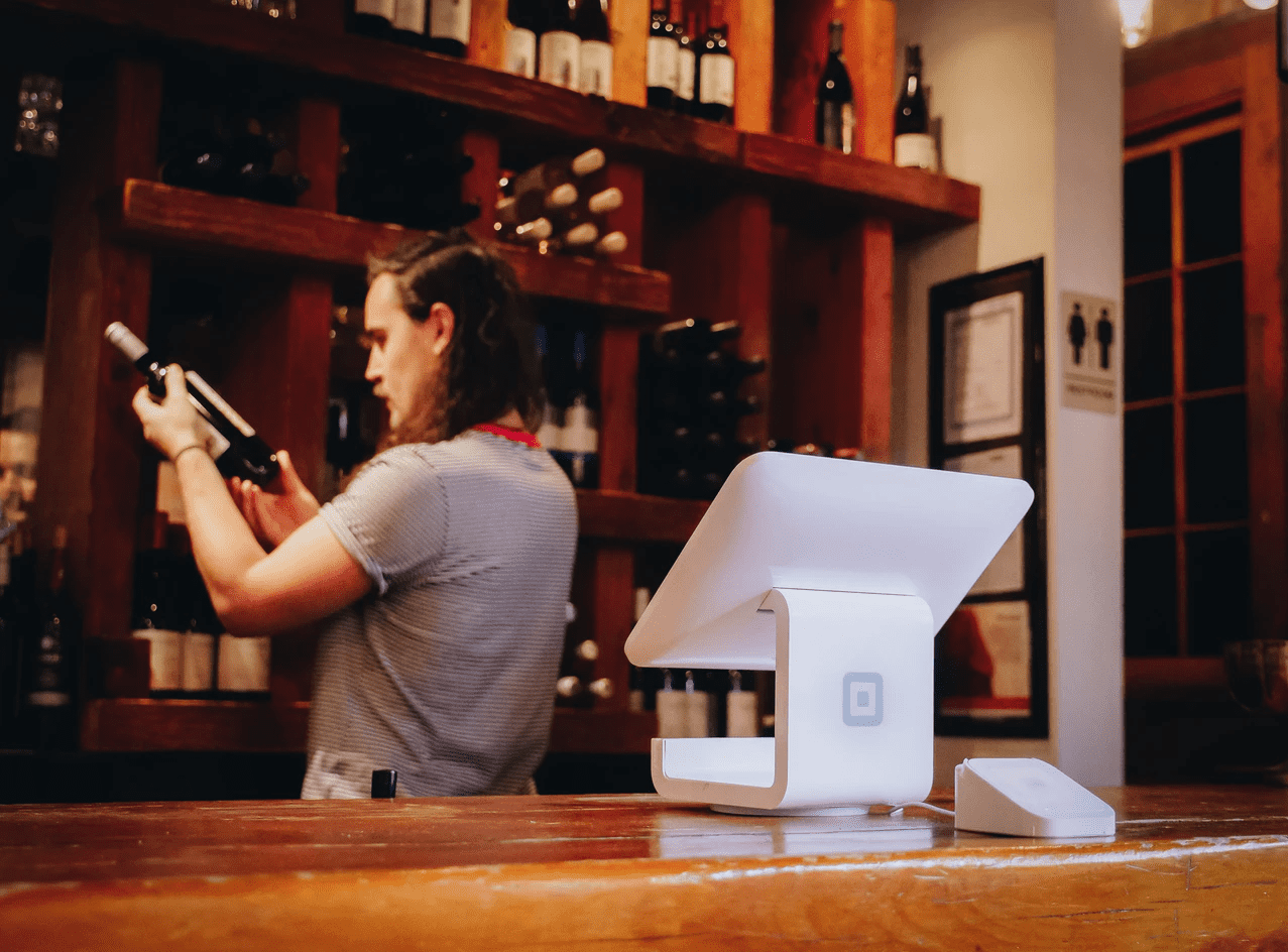 man working in a bar looking at a bottle