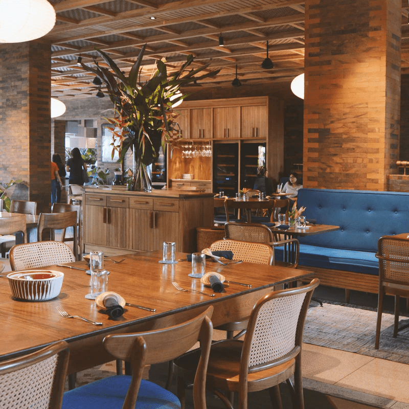 Empty restaurant with wooden tables and blue cushioned chairs