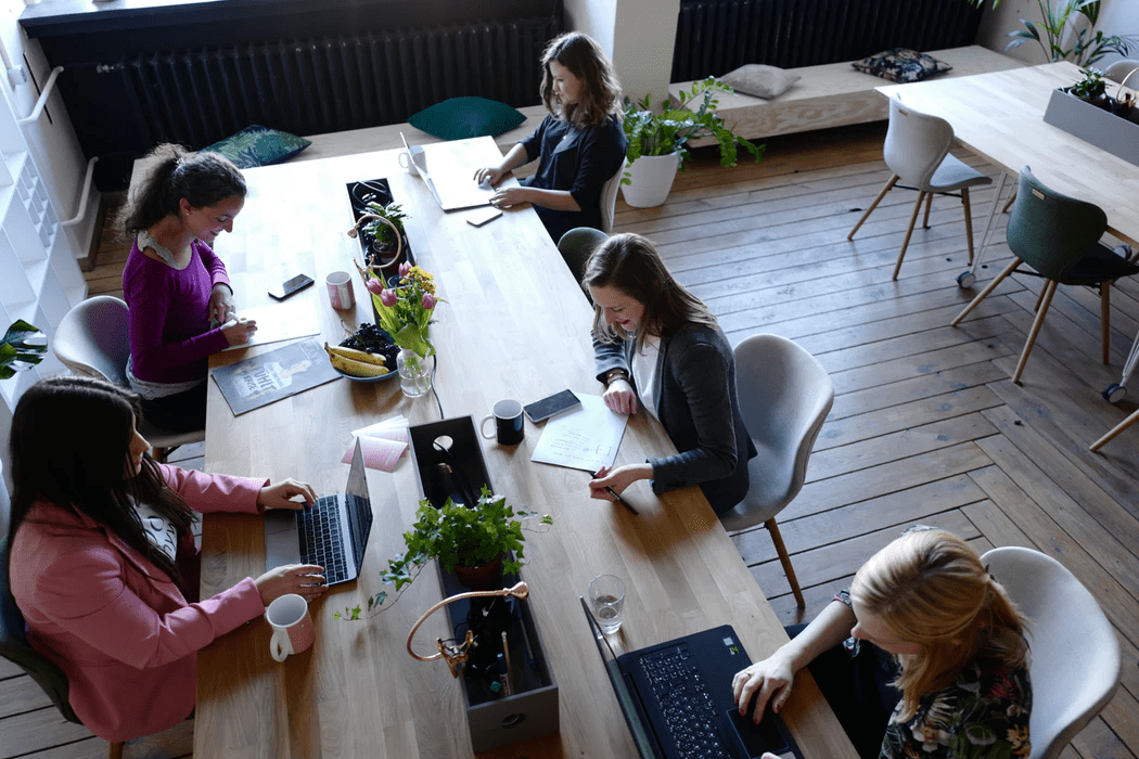 Team members working on laptops at a wooden table