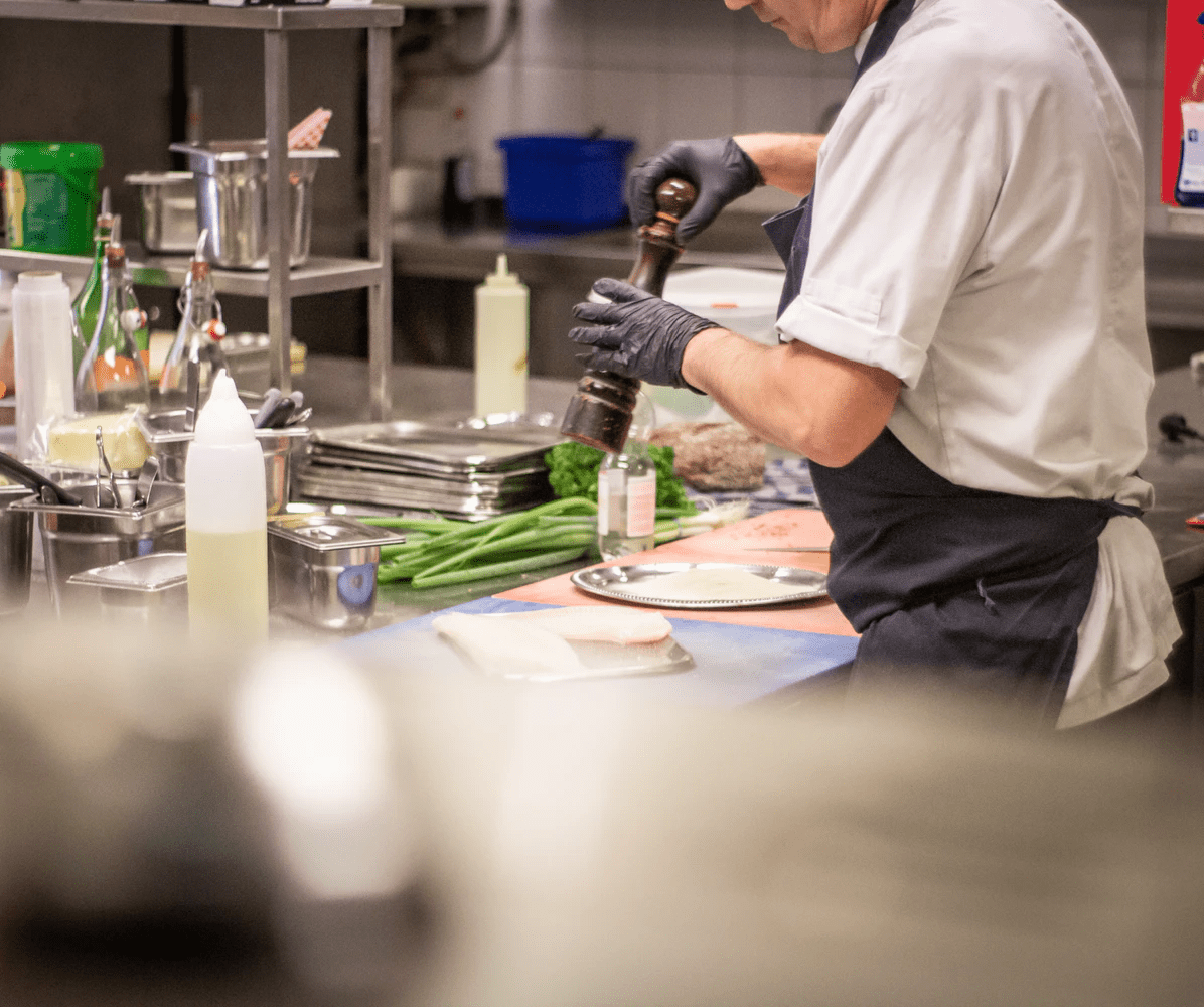 Mann, der das Essen im BOH eines Restaurants zubereitet