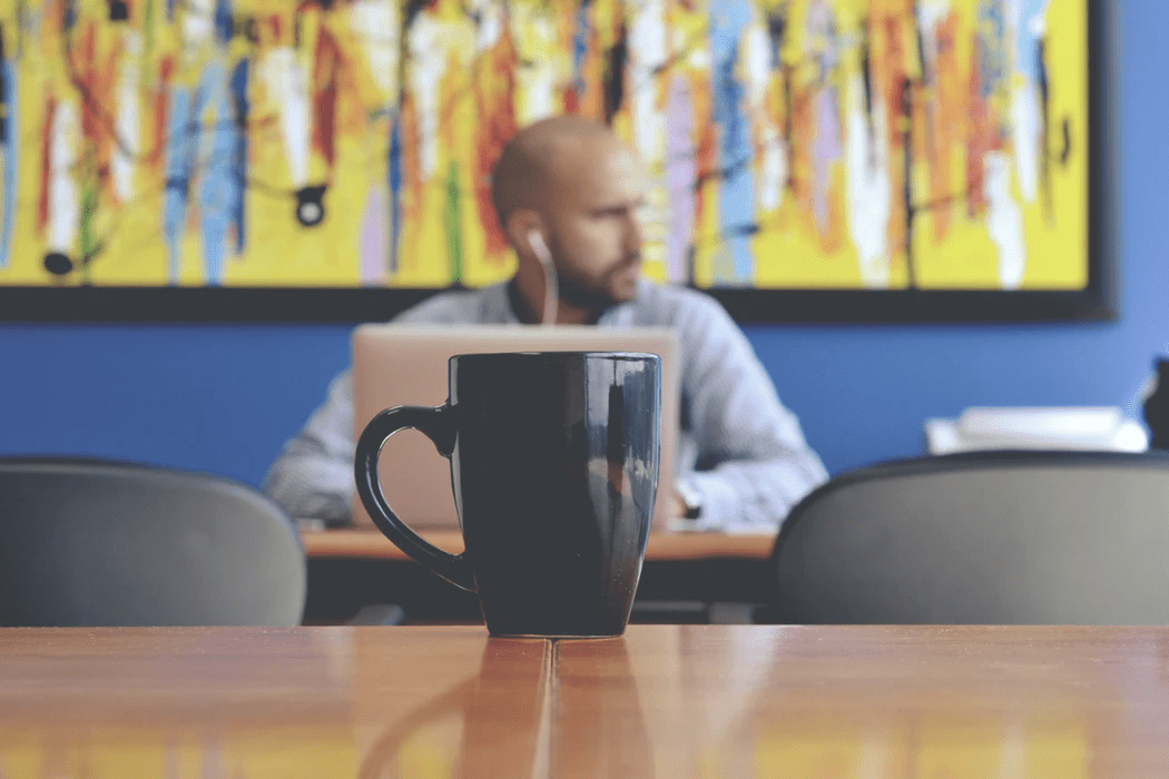 Man in cafe on his laptop with coffee mug on the table in front of him