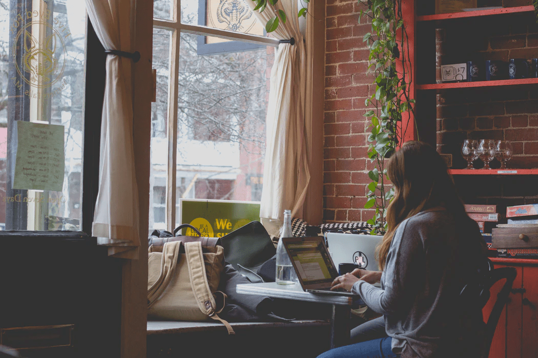 Business owner researching employee satisfaction on her laptop in a cafe