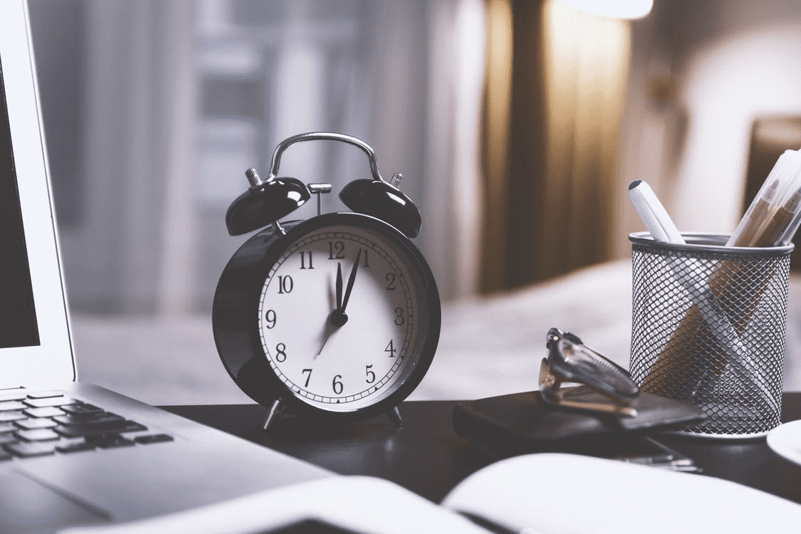 clock, pen cup, and laptop on a desk