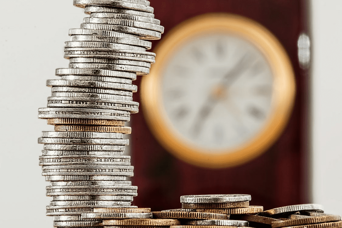 coins stacked high with clock in the background