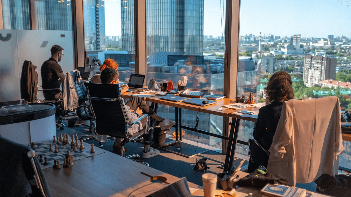 Coworkers at a long table in front of glass wall overlooking a city