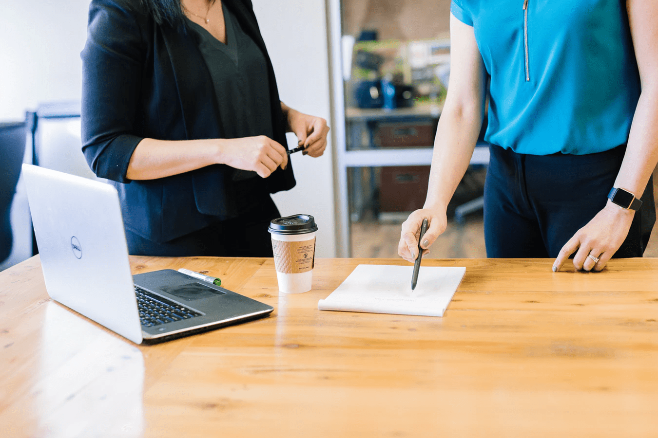 Business owners using notebook and laptop to discuss employee feedback