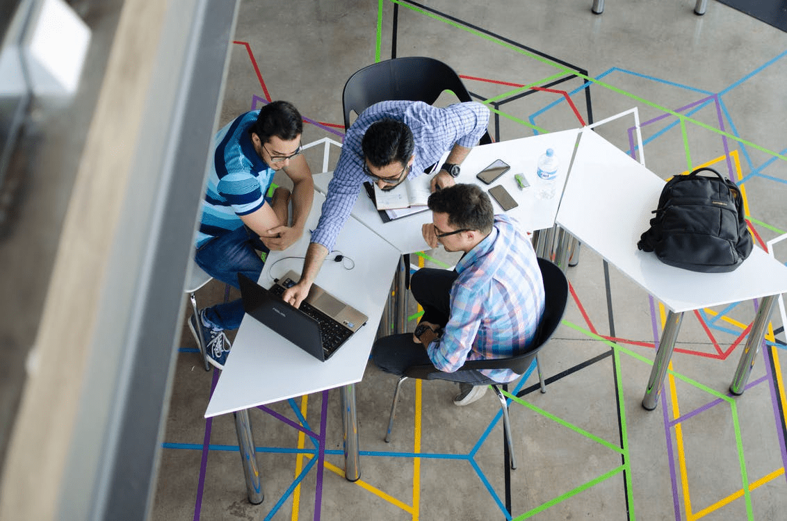 Three entrepreneurs discussing team-building games around a laptop