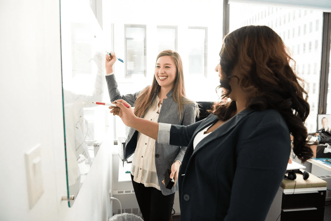 two women entrepreneurs working at a whiteboard