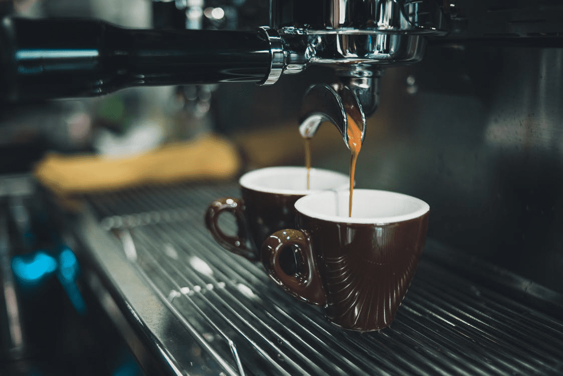 coffee being made in two brown mugs