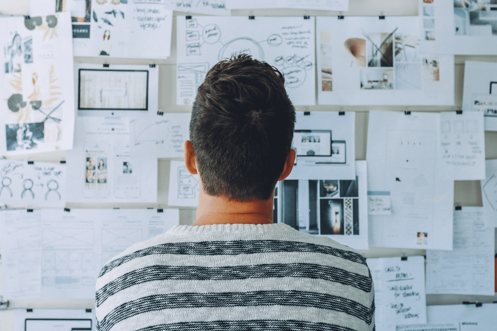 man staring at bulletin board of charts and graphs