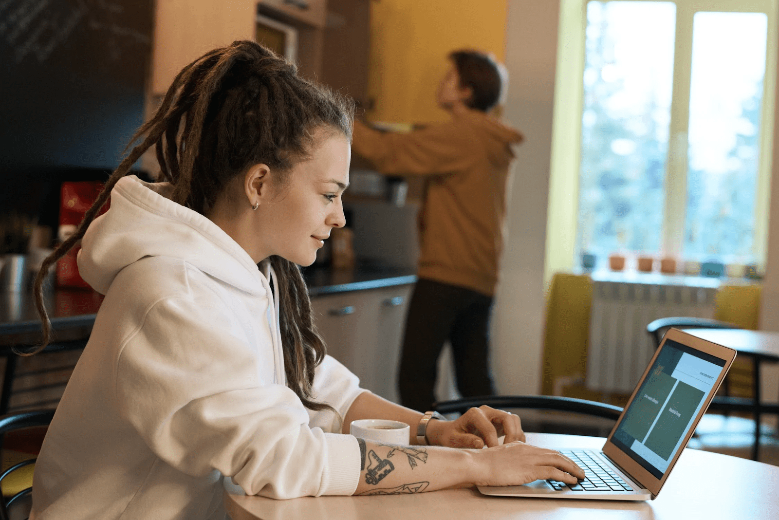 Woman working from home in her kitchen while her husband cooks