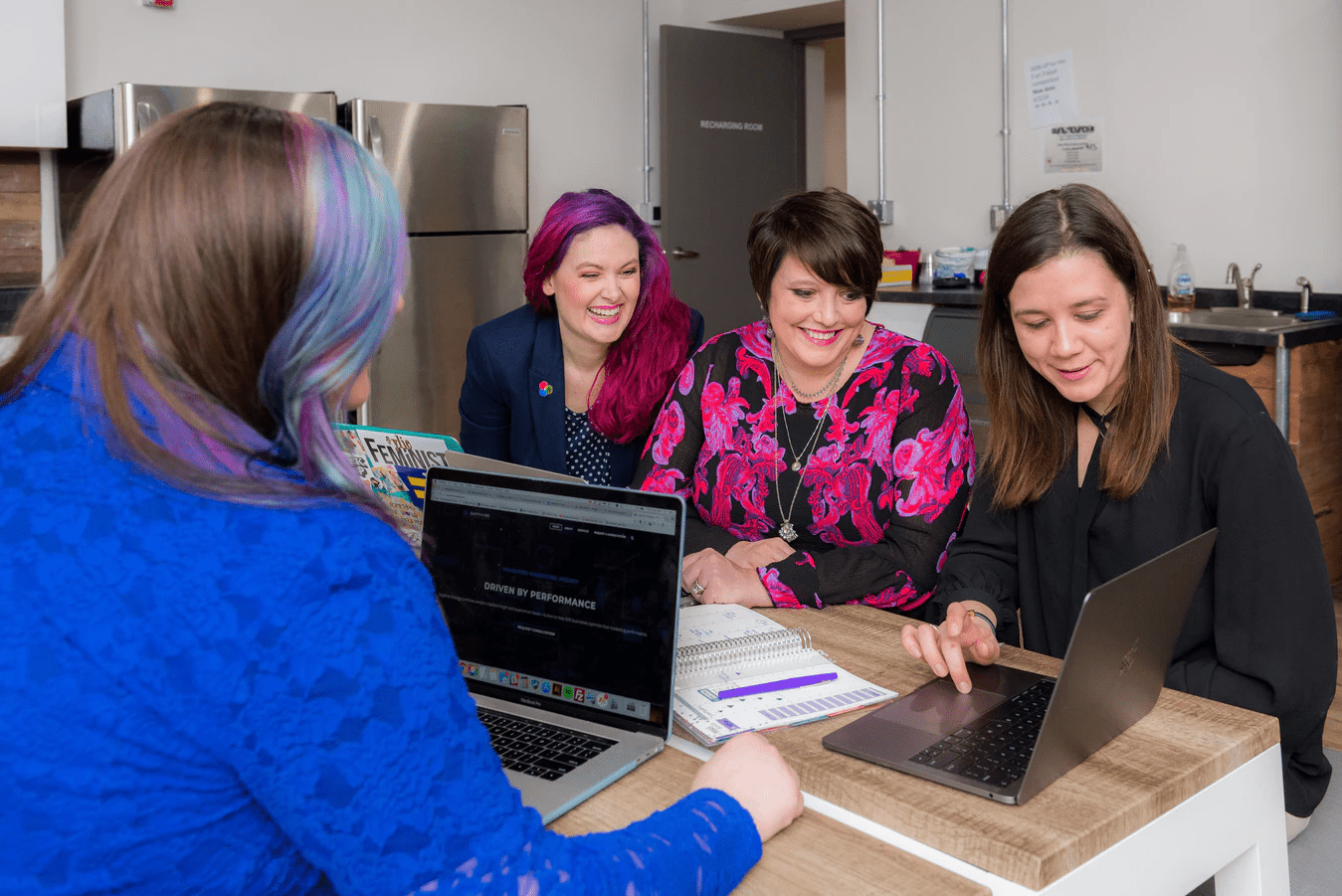 group of women looking at a dress code policy on laptops