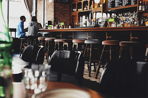 Two people sitting at the bar in a pub type of restuarant