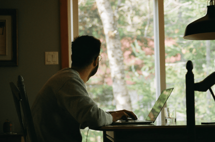 man working remotely looking out his window