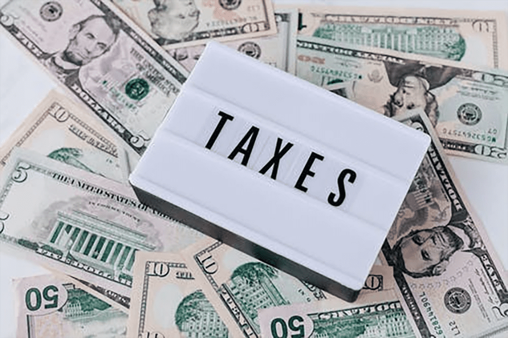 Sign with the word taxes on it on top of a pile of money