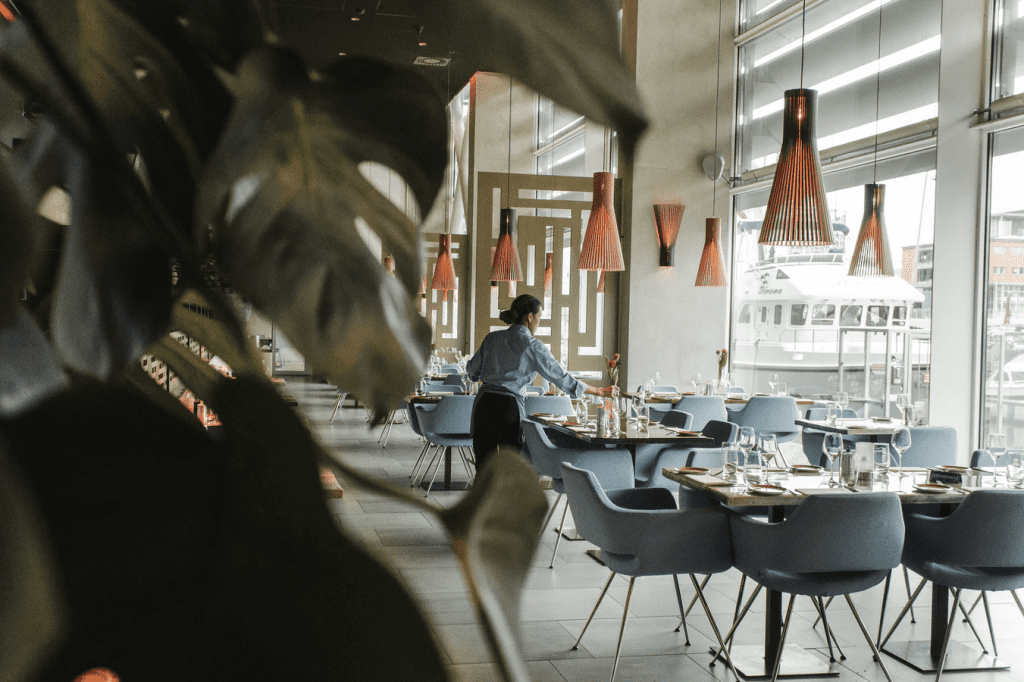 Inside a restaurant with waitress setting up tables for service