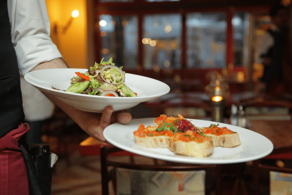 Waiter holding a salad and appetizer dish in one hand