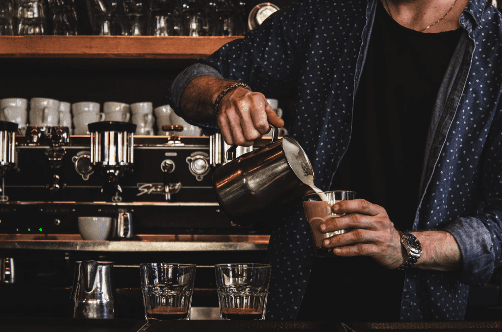 Contingent worker barista pouring cream in coffee