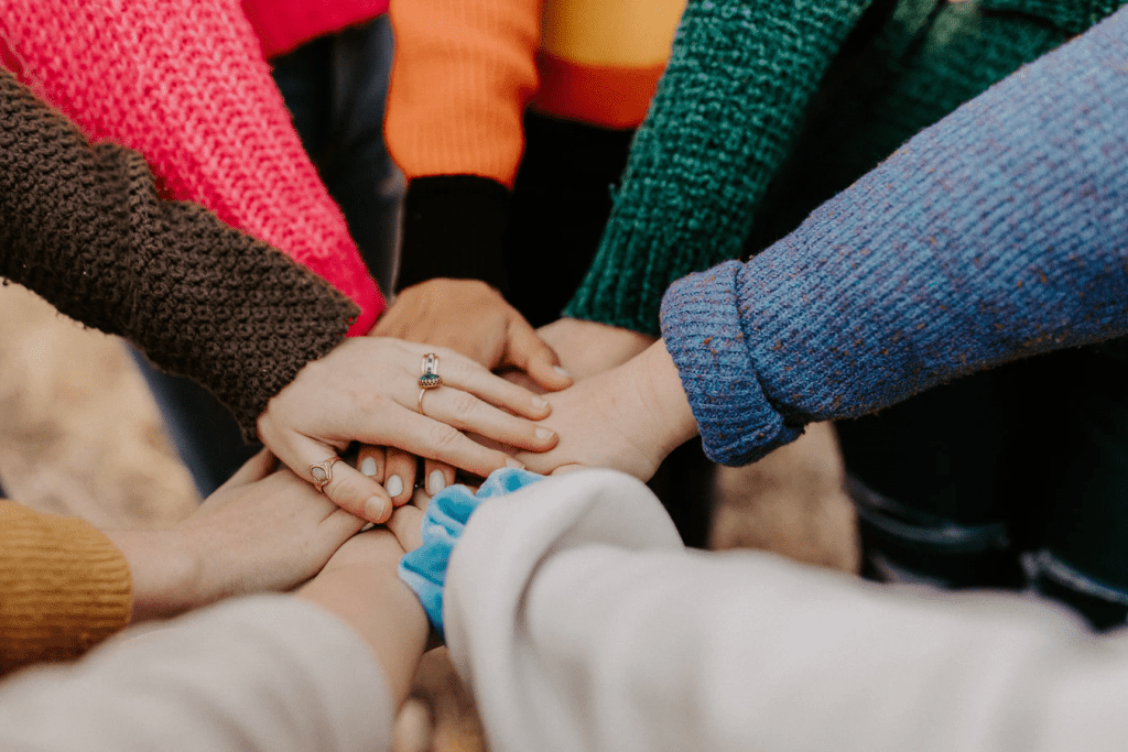 People in a circle with their hands out on top of each other