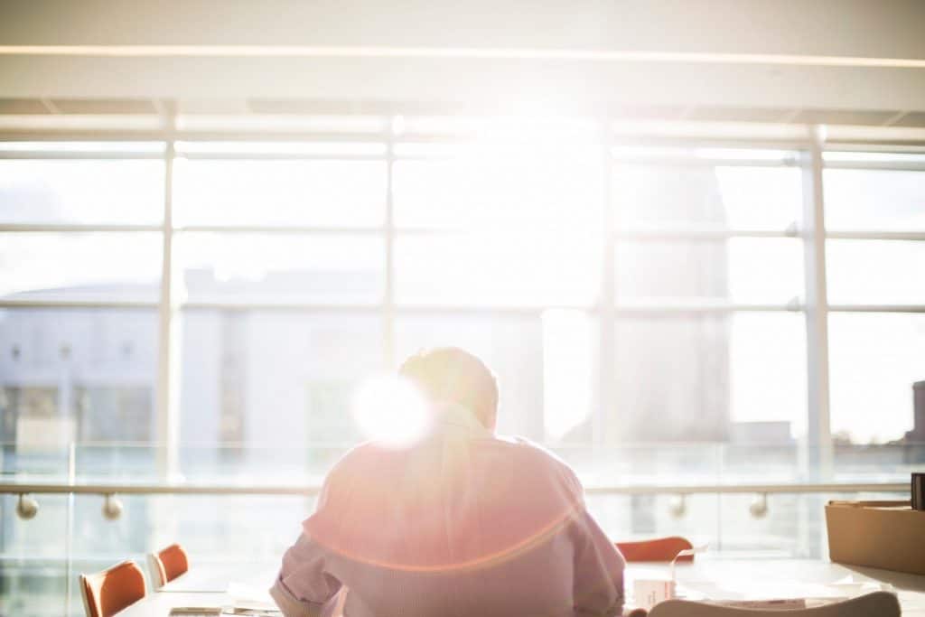 Man sitting in office building in front of window with sun shinning through