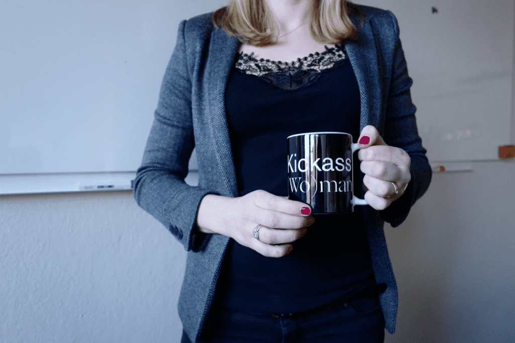 charismatic leadership who is holding a coffee mug that says Kickass Woman