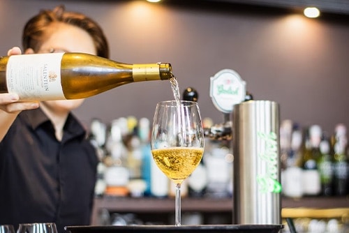 Person pouring a glass of white wine