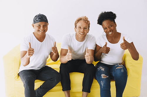 Three coworkers smiling and giving thumbs up