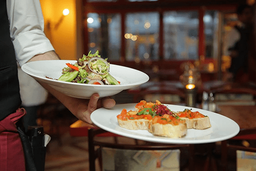 Server at a restaurant holding plates of food